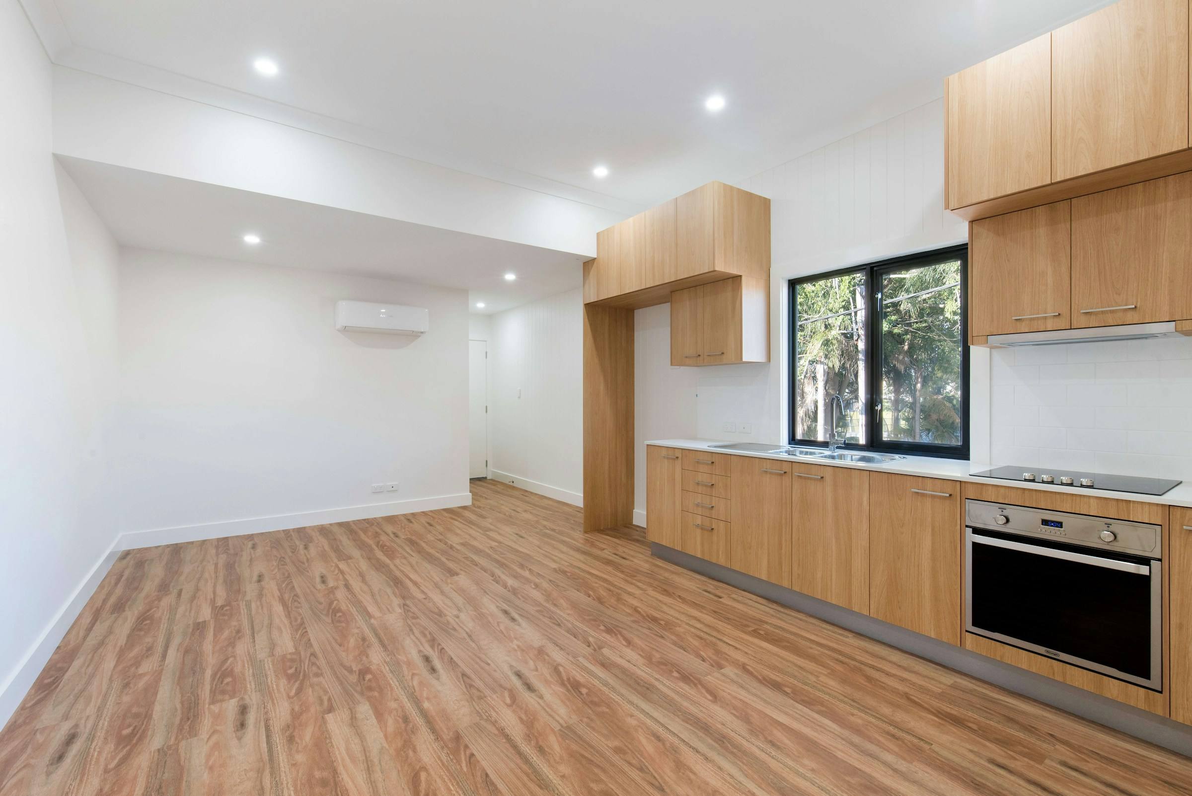 Empty apartment ready for new tenants, with wood-look floors and a kitchen along one wall